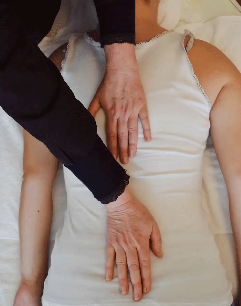 Mains d’un praticien posées sur le dos d’une personne allongée