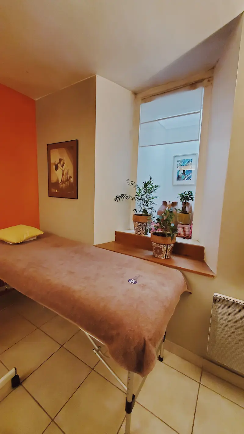 Salle de soin avec table de massage près d’une fenêtre
